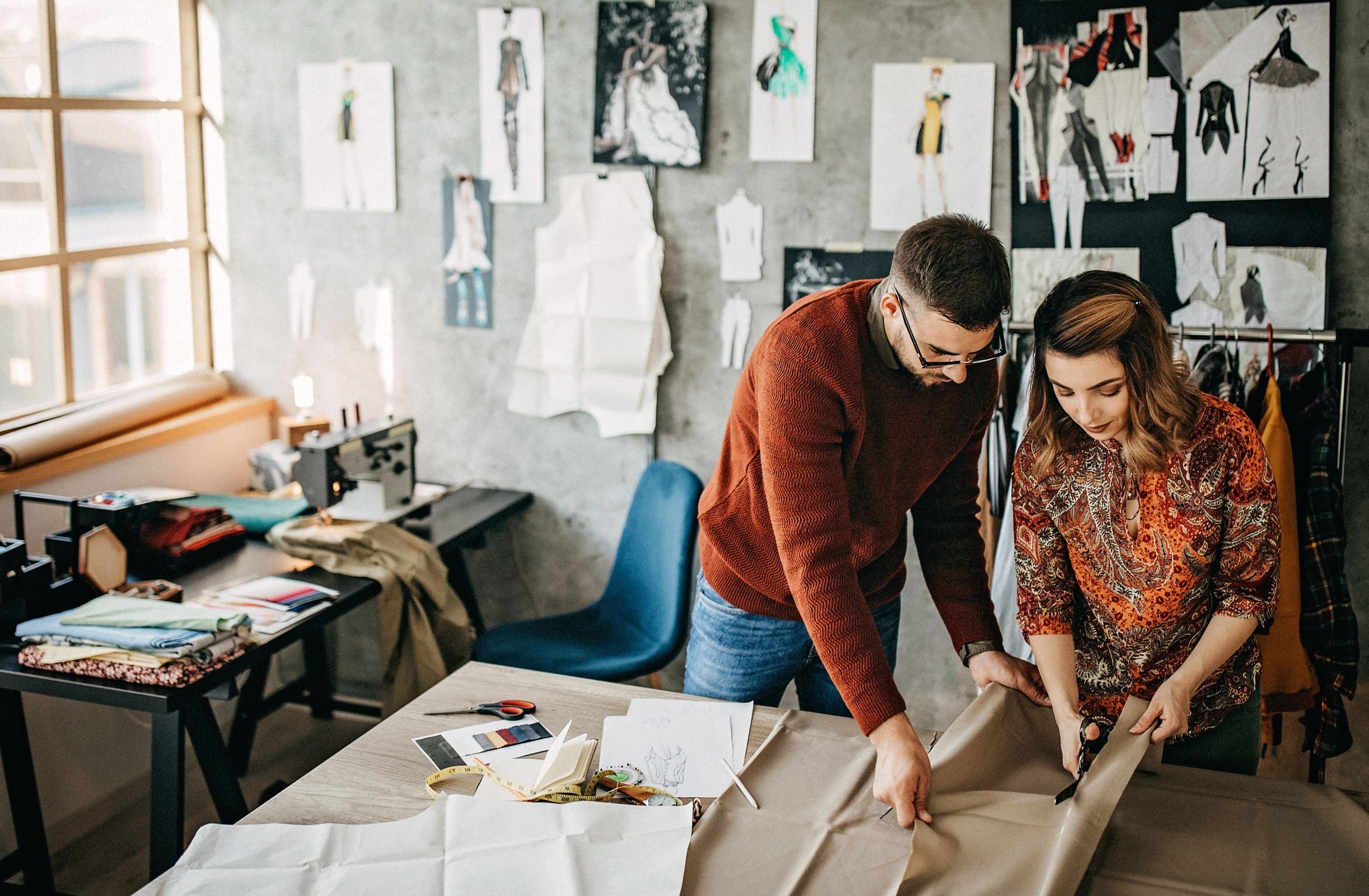 Two apparel employees cut fabric together